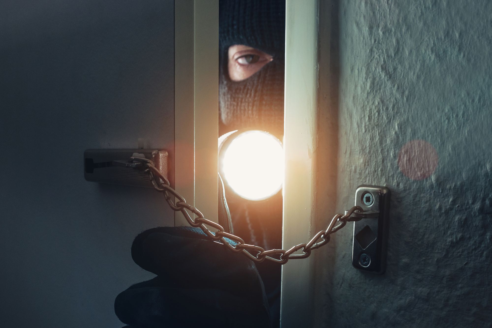 Einbrecher leuchtet mit Taschenlampe in Wohnung